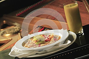 Closeup of oatmeal with strawberries and kiwis on a piano with a glass of green juice on it