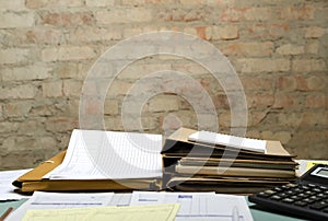 Closeup of office table and stacks of folders, documents on it against brick wall.Empty space