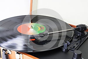 Closeup of an old-fashioned suitcase record player and turntable with a spinning vinyl record, isolated on white