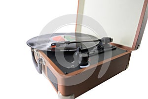 Closeup of an old-fashioned suitcase record player and turntable with a spinning vinyl record, isolated on white