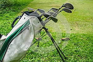 Closeup old golf bags on green. Set of golf clubs over green field background