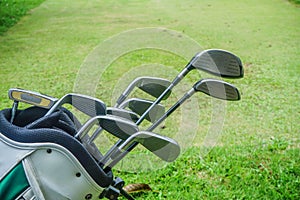 Closeup old golf bags on green. Set of golf clubs over green field background