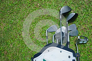 Closeup old golf bags on green. Set of golf clubs over green field background