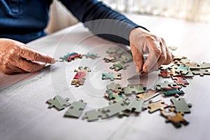 Closeup of the old hands playing with jigsaw puzzles