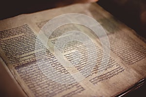 Closeup of an old Hebrew Bible on the table under the lights with a blurry background