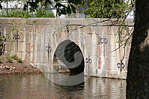 a closeup of an old historic stone bridge with ornaments over a moat