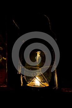 Closeup of an old hurricane lantern lighting and shinning with a flame of fire at night. Village oil lantern burning with kerosene