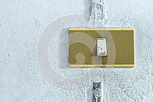 A closeup in a old light switch on the old white wall.