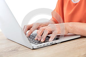 Closeup old man`s hands typing enter on laptop keyboard