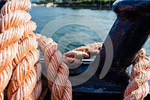 Closeup of an old red frayed boat rope, water background with landscape