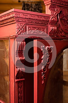 Closeup of old renovated cupboard with opened door with fantastic hand carved ornaments with wooden house walls in