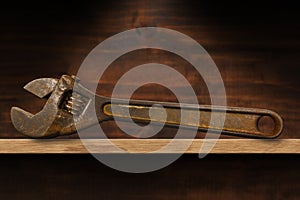 Old Rusty Adjustable Wrench on a Wooden Shelf