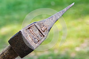 Closeup of an old rusty axe under sunlight with greenery on the blurry background