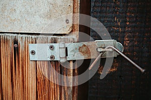 Closeup of an old rusty painted metal latch with a bent nail keeping it shut