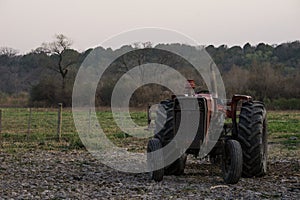 Closeup of an old and rusty tractor in the middle of the field on a gloomy day
