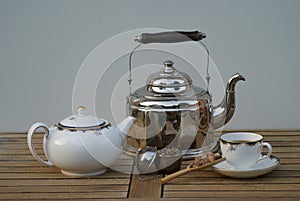 Closeup of an old water kettle with teapot, teacup, tea infuser and candy