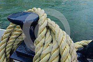 Closeup of an old yellow frayed boat rope, water background with landscape