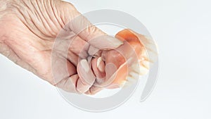 Closeup of older womans hand holding dentures