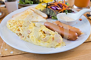 Closeup of omelet with orange juice, croissants, cereals and fruits on wooden table