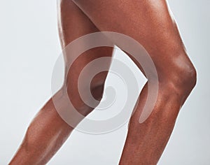 Closeup of one African American fitness model posing and looking muscular. Confident black male athlete isolated on grey