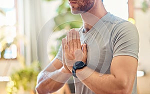 Closeup of one caucasian man meditating in harmony with hands together in namaste gesture while practising yoga at home