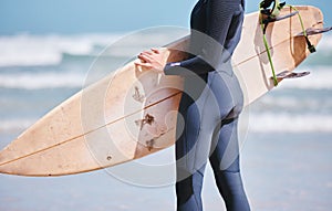Closeup of one caucasian woman holding a surfboard and wearing wetsuit at the beach. One female only surfing as a fun