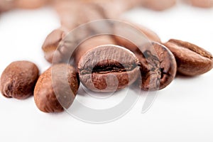 Closeup on one coffee bean isolated on blur roasted beans background. Macro grain coffee black espresso.