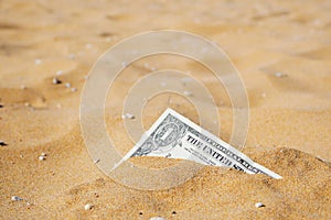 Closeup of one dollar banknote corner buried in the sand. Copy space