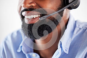 Closeup of one happy african american call centre telemarketing agent with big smile talking on headset while working in