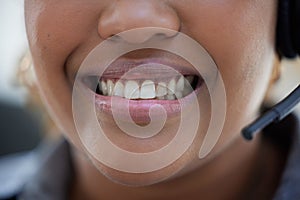 Closeup of one happy african american call centre telemarketing agent with big smile talking on headset while working in