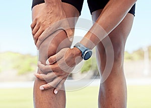 Closeup of one man holding sore knee from exercising outdoors. Uncomfortable athlete suffering with painful leg injury