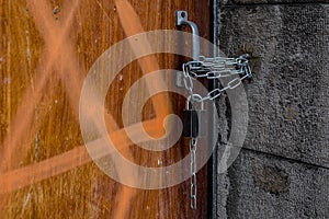 Closeup of one old wooden door locked by padlock and chain.