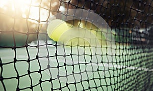 Closeup of one yellow tennis ball with motion blur hitting a net during a game on a court. Fast ball moving with speed