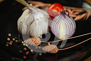 Closeup of onion and garlic with species on a dark surface