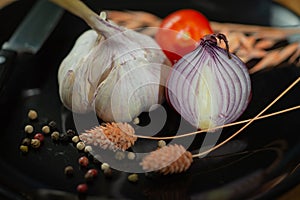 Closeup of onion and garlic with species on a dark surface