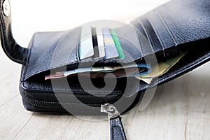 Closeup of an opened black wallet and showing cards with money in it
