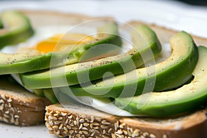 closeup of an openface sandwich with sliced avocado and egg