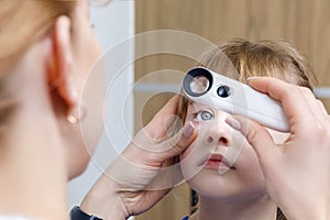 A closeup of an ophthalmologist checking the eye of a child