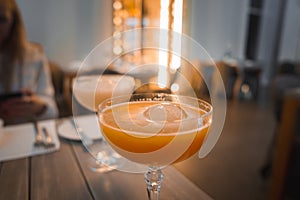 Chilled Orange Cocktail in Elegant Glass with Cozy Dining Ambiance photo