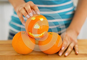 Closeup on orange with funny face in hand of woman