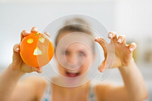 Closeup on orange with hallowing face in hand of woman