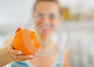 Closeup on orange in hand of young woman