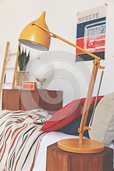Closeup of orange lamp on bedside table in vintage bedroom, real photo