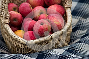 organic red apple in a  wooden basket on blue napkin background