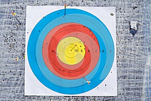 Closeup on outdoor archery target board with arrow on bullseye