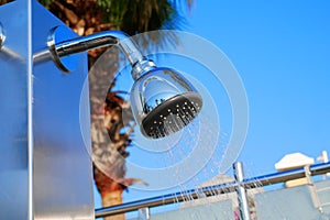 Closeup of outdoor shower head. Outdoor pool shower. Water running from poolside shower sprinkler