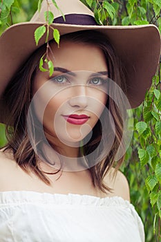 Closeup outdoors portrait of young woman face. Pretty girl in hat