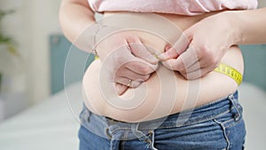Closeup of overweight woman using measuring tape. Concept of dieting, unhealthy lifestyle, overweight and obesity