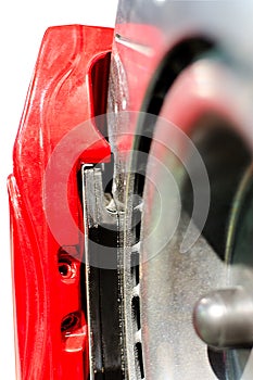 Closeup pads on disc car brake in red caliper