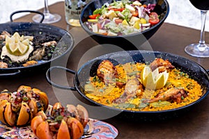 Closeup of Paella and Arros negre served with vegetable salad in a restaurant